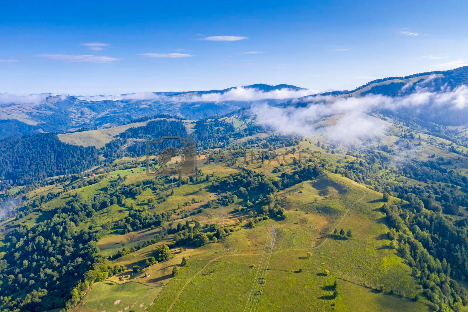 Aerial view of pasture, forest and fog during summer, Romanian Carpathians.