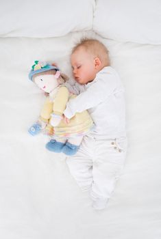 Baby sleeping while embracing a plush doll