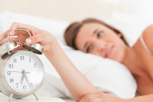 Woman silencing her alarm clock, focus on the clock