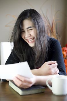 Teenage girl or young woman happily reading note in hand