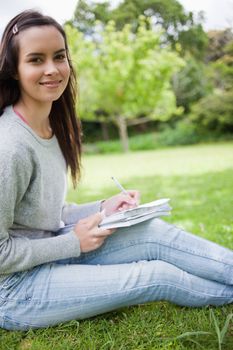 Young smiling girl sitting in the countryside while doing her ho