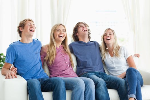 Laughing friends sit on the couch together 