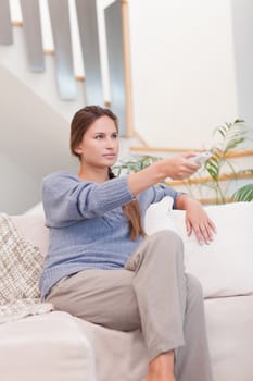 Portrait of a woman switching channel with a remote