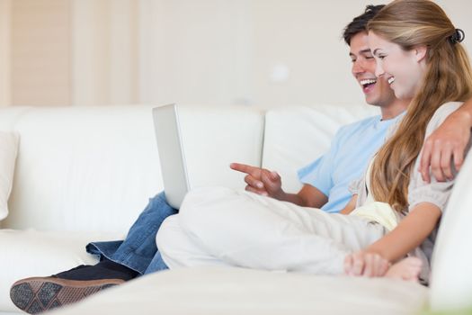 Happy couple using a laptop in their living room
