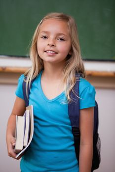 Portrait of a blonde schoolgirl holding her books