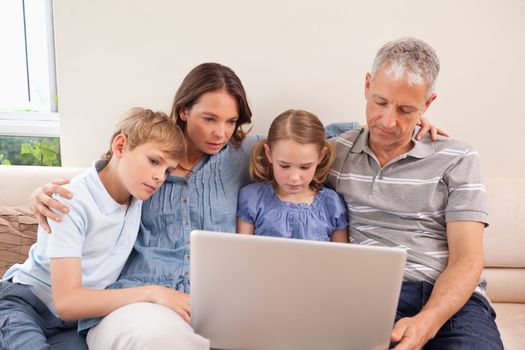 Family sitting on a sofa using a laptop