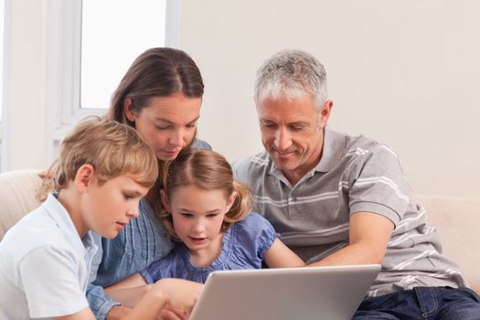 Happy family sitting on a sofa using a laptop