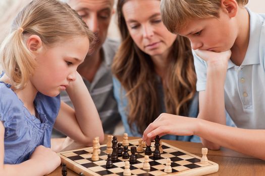 Close up of serious children playing chess in front of their par
