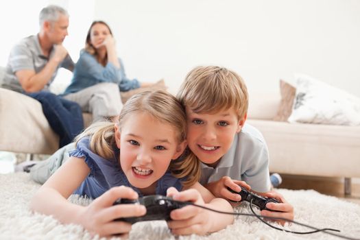 Cheerful children playing video games with their parents on the 