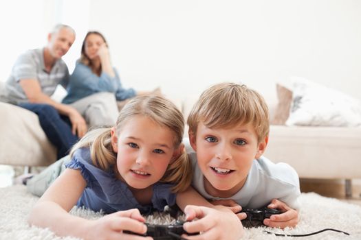Playful children playing video games with their parents on the b