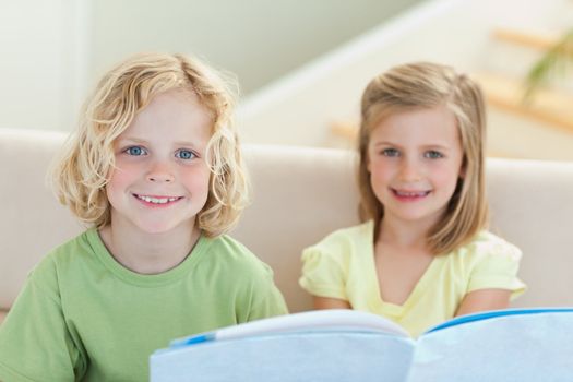 Siblings reading booklet on the sofa