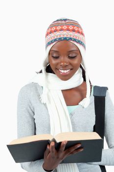 Close up of smiling student in winter clothes reading in her boo