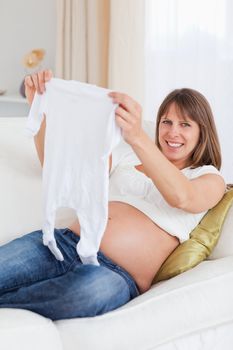 Good looking pregnant woman holding a baby grow while lying on a