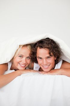 Portrait of a smiling couple under a duvet
