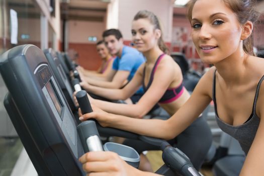 Four people smiling and riding on an exercise bike
