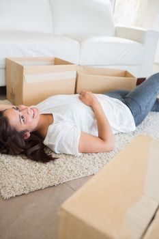 Woman lying on the carpet next to moving boxes