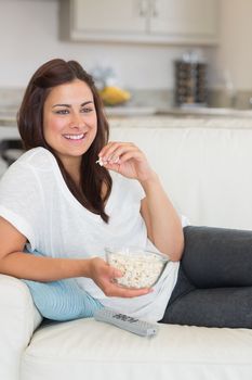 Woman eating popcorn while relaxing on the sofa