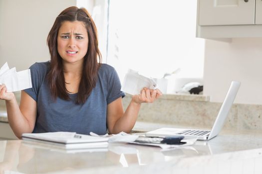 Woman looking troubled while holding bills