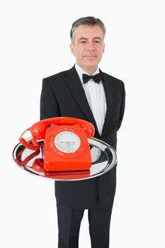 Well-dressed waiter holding a phone on a silver tray