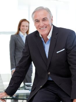 Senior businessman sitting on a conference table smiling at the camera