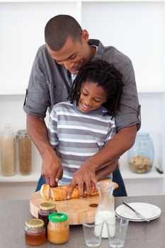 Happy father slicing bread with his son in the kitchen