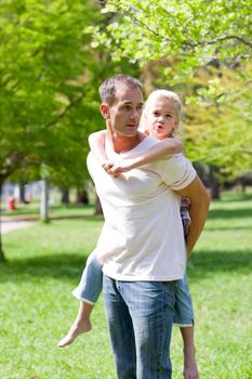 Joyful father giving his daughter piggy-back ride 