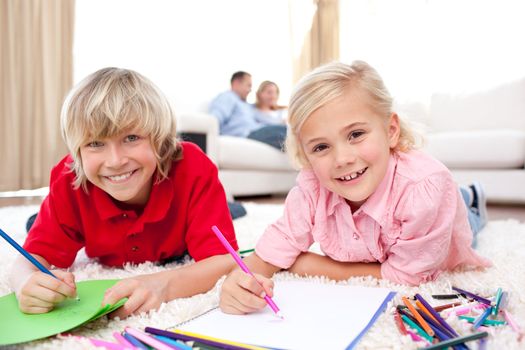 Lively siblings drawing lying on the floor