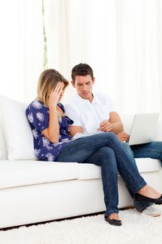 Distressed couple doing their accounts sitting on sofa
