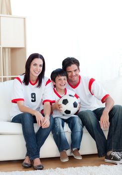 Jolly young family watching a football match 