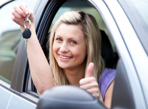 Lively female driver showing a key after bying a new car 