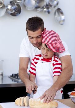 Father helping his son cutting bread in kitchen