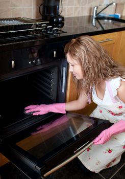 Young woman cleaning the oven 