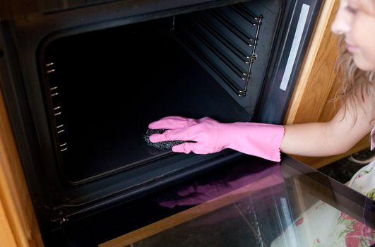 Close-up of a woman cleaning the oven 