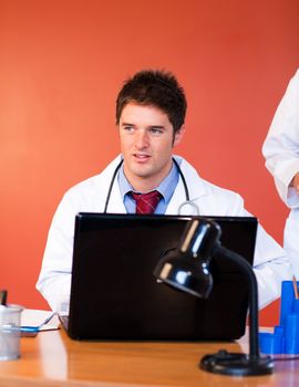 Attractive doctor using a laptop in office
