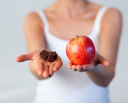 Beautiful woman showing chocolate and apple focus on chocolate 