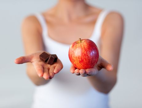 Close-up of woman showing chocolate and apple focus on apple 