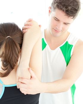 Young physical therapist checking a woman's shoulder