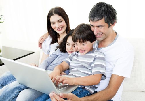 Glad family using a laptop sitting on sofa
