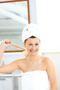 Lively woman washing her back smiling at the camera 
