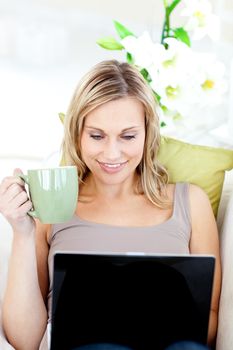 Caucasian woman sitting in front of her laptop and holding a cup