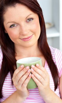 Glad woman holding a cup of coffee in the kitchen