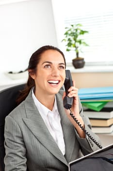 Cheerful hispanic businesswoman talking on phone in front of her