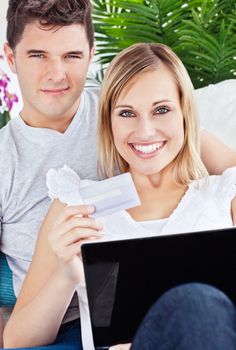 Glad couple buying online with credit card and laptop laying on 