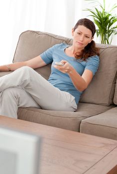 Serious woman changing channel while relaxing in the living-room
