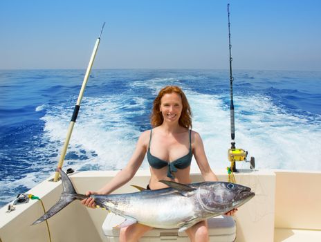 bikini fisher woman holding bluefin tuna on boat
