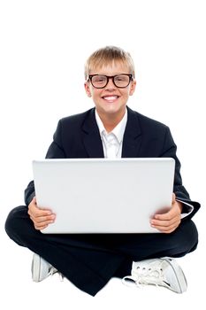 Cheerful young kid sitting on the floor with a laptop