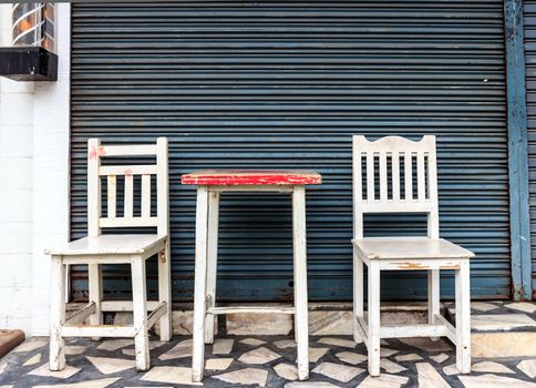 Set of Wooden Chairs in front of Steel Shutter Door