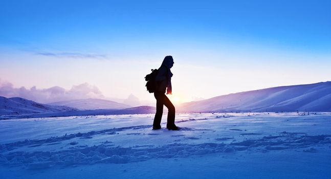 Woman traveler hiking in winter mountains