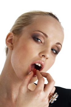 Close-up portrait of young blond model eating a candy over white.