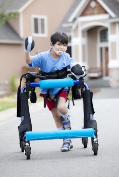 Six year old disabled boy walking in walker down the street